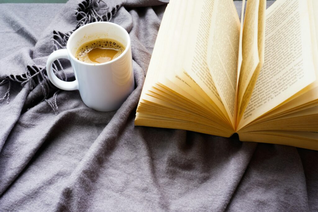 Warm coffee and an open book on a cozy blanket, perfect for a relaxing read.